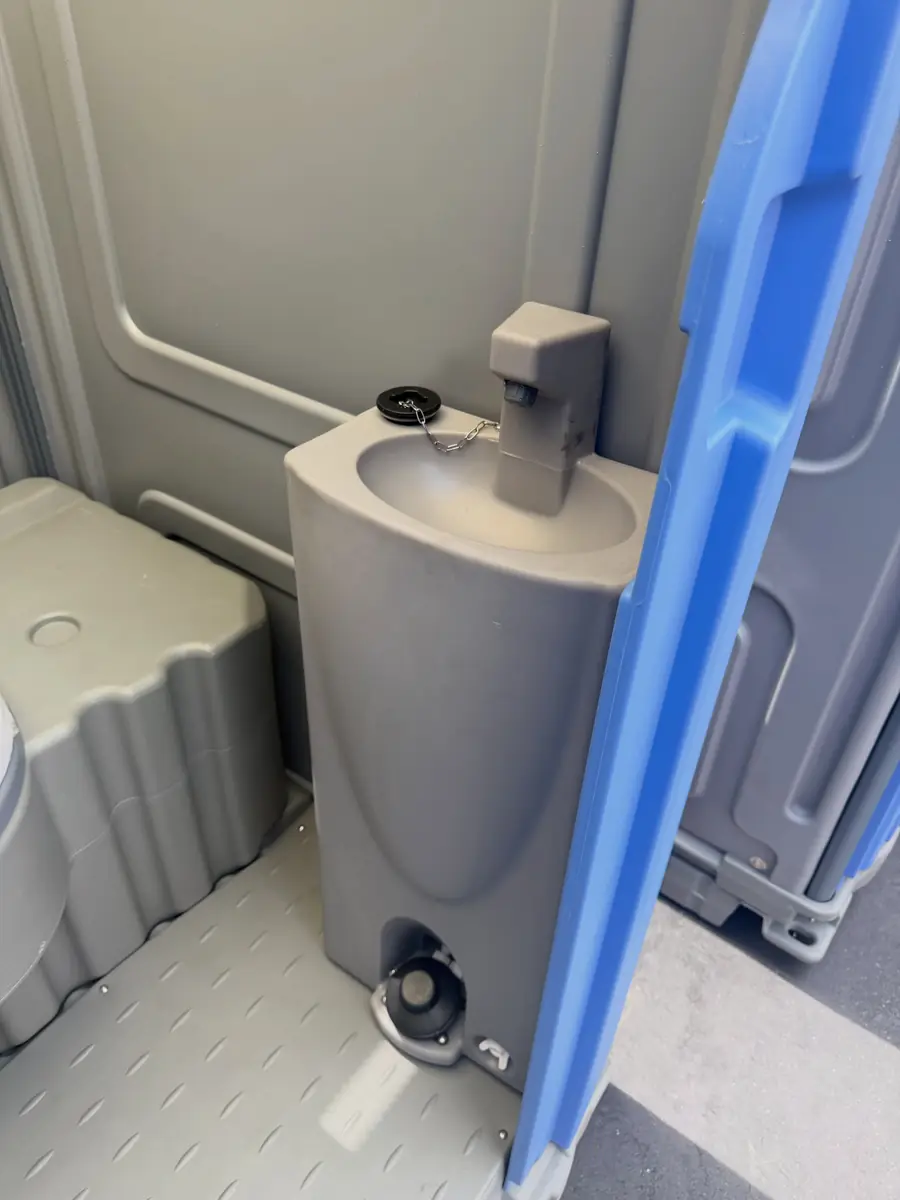Built-in foot-pump hand sink mounted inside a portable toilet