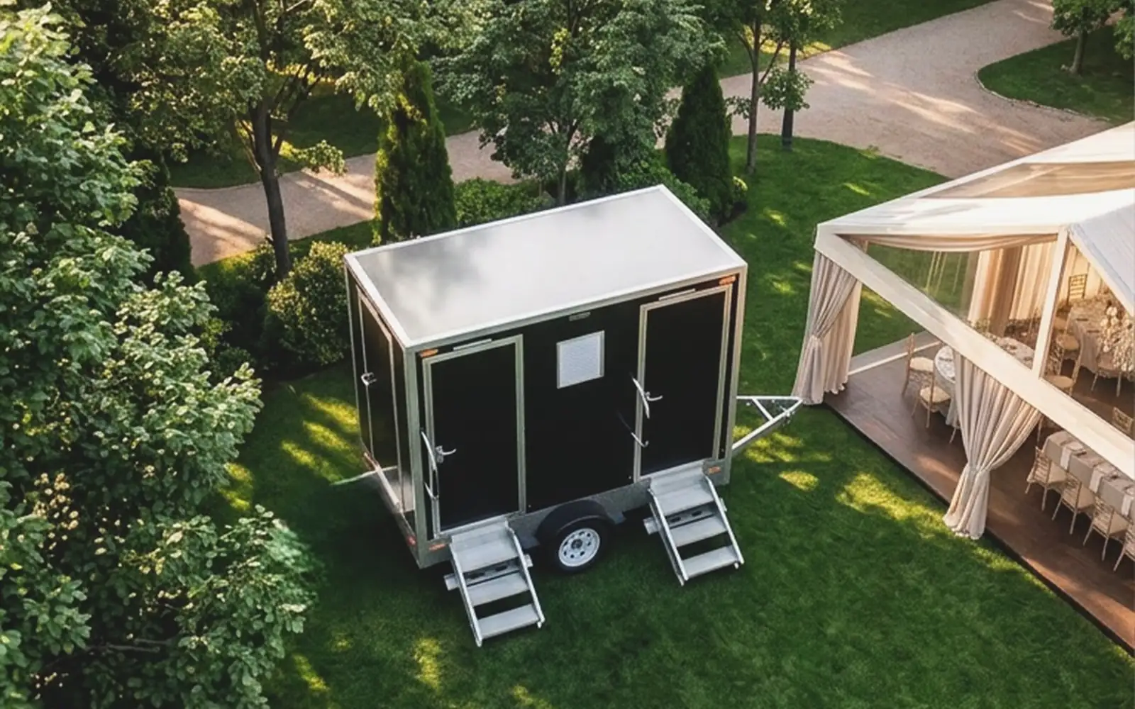 Aerial view of a restroom trailer on a lawn beside a wedding tent