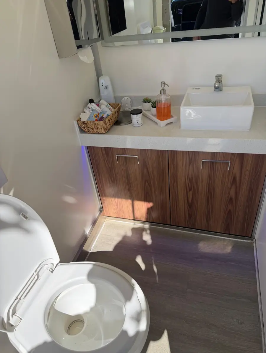 Restroom trailer vanity with wood cabinet, vessel sink and amenities basket